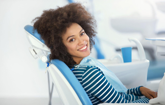 Woman in dental chair smiling at dentist's office during examination or treatment.