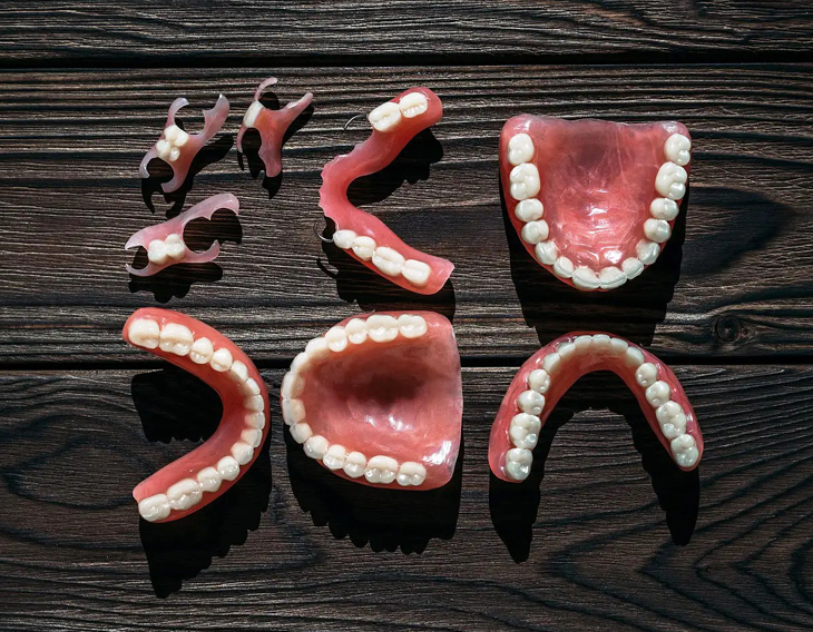 Dental models displaying teeth and gums arranged on dark wood surface for educational purposes.