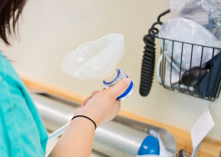 Child holding clear dental retainer at sink with cleaning supplies nearby.