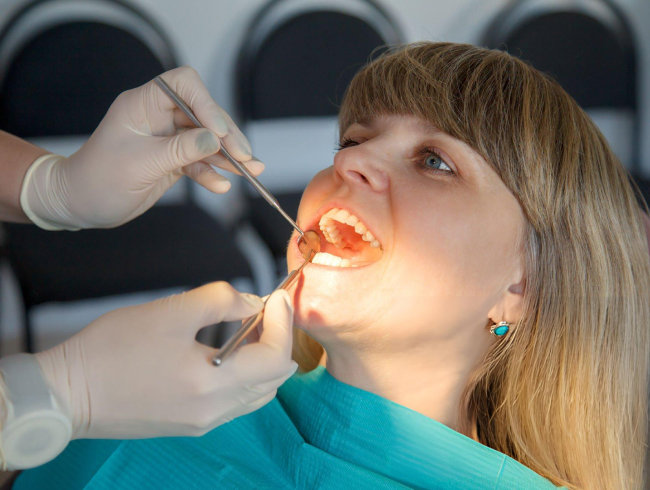 Dentist examining patient's teeth during dental checkup in clinical office setting.